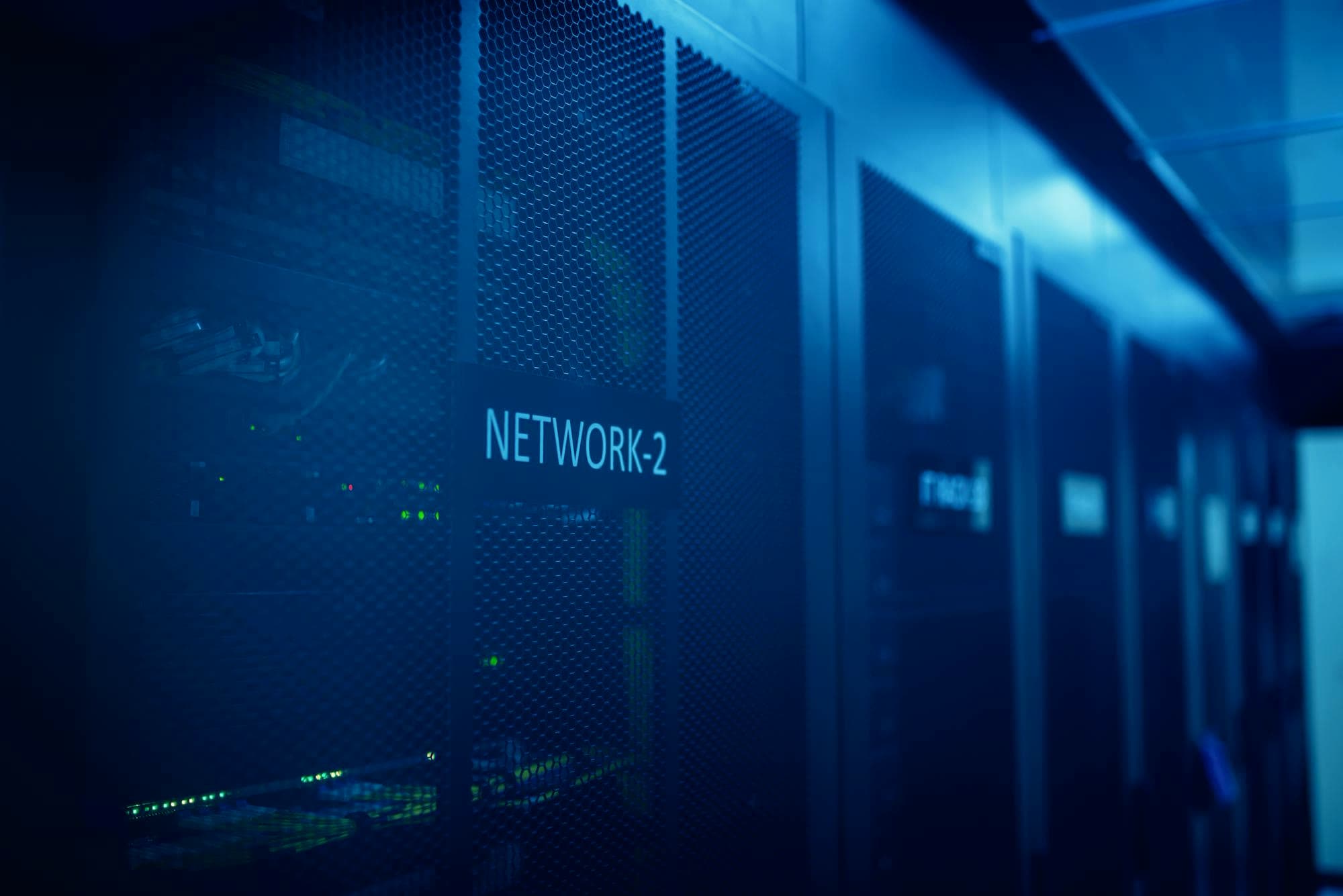 A server room glowing in blue light, racks receding into the dark